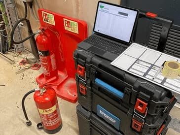 Fire extinguisher servicing A safety inspection of foam fire extinguishers. Results being recorded on a laptop