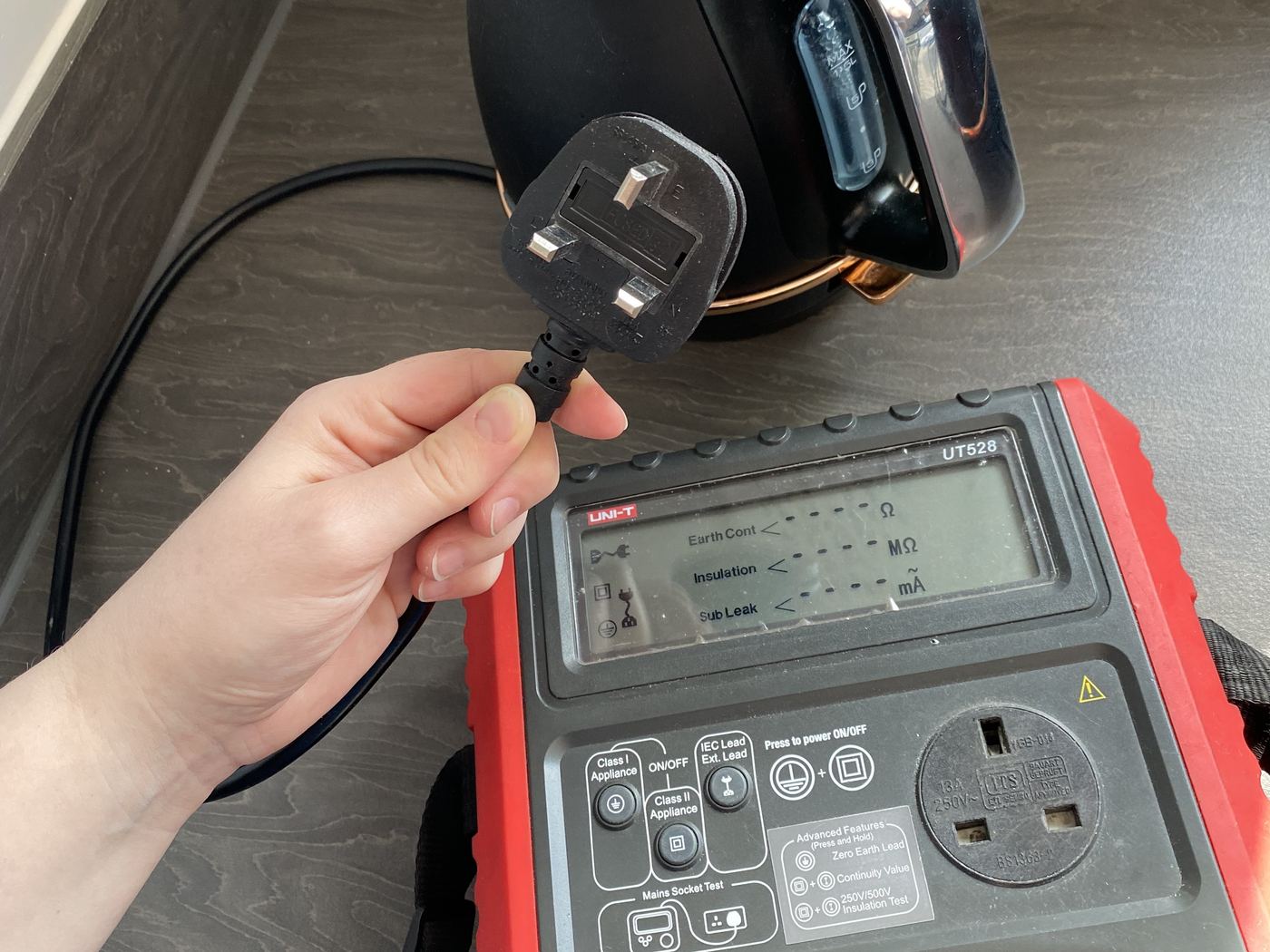 Kettle plug being connected to a UNI-T UT528 portable appliance tester